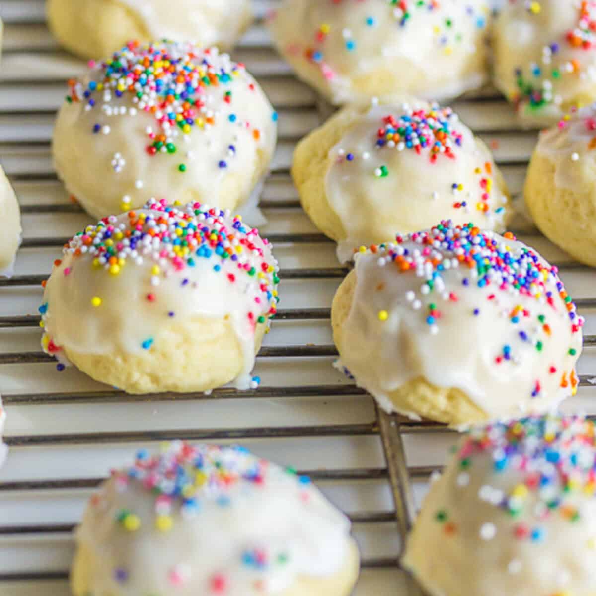 italian wedding cookies or anginetti with colored sprinkles on wire rack.