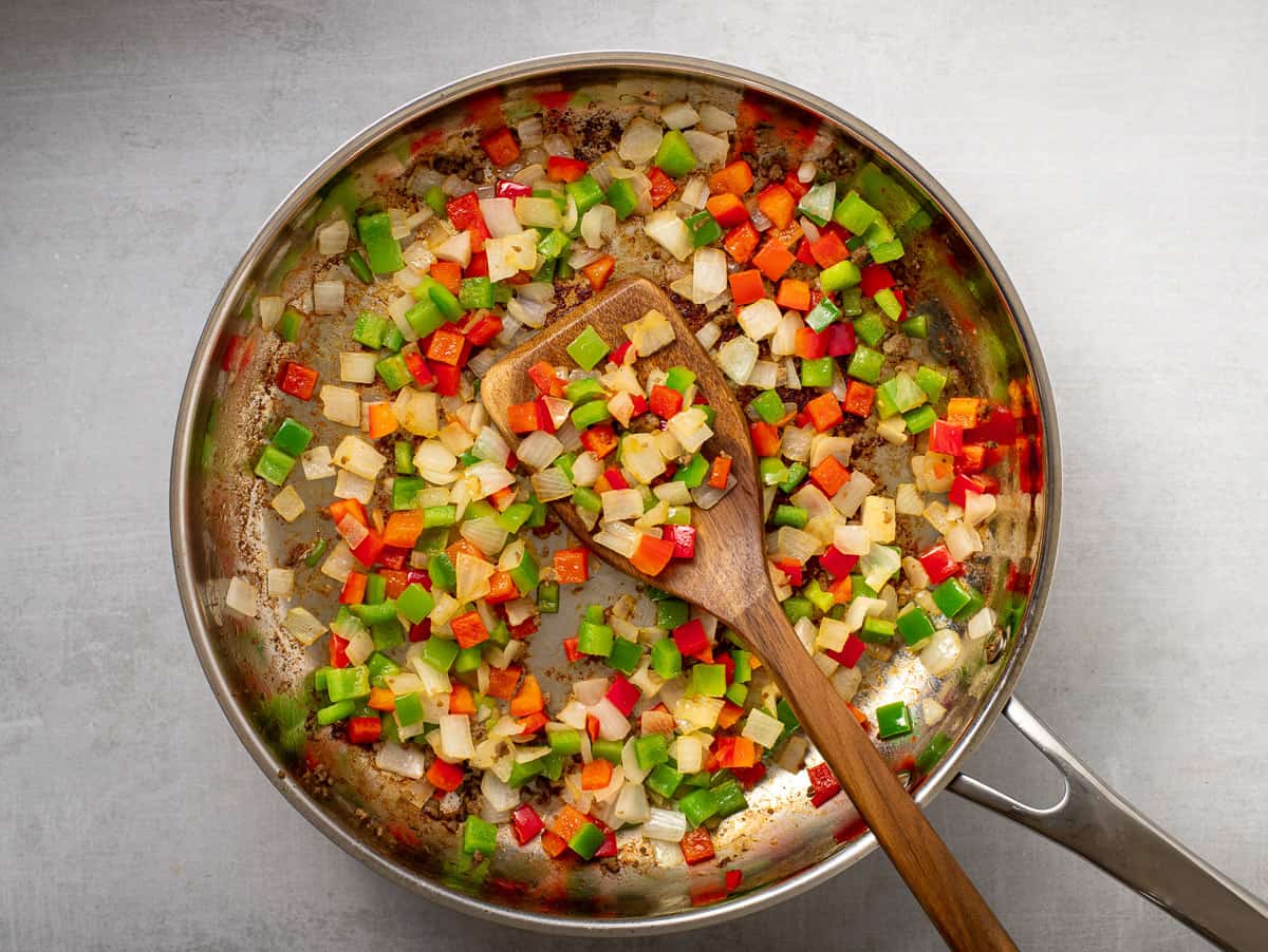 Pan with cooked vegetables and wooden spoon.