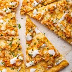 buffalo chicken pizza sliced on parchment paper.