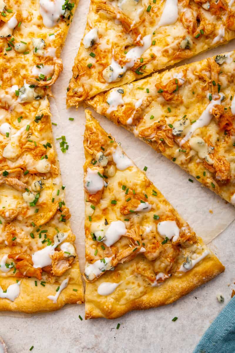 buffalo chicken pizza sliced on parchment paper.