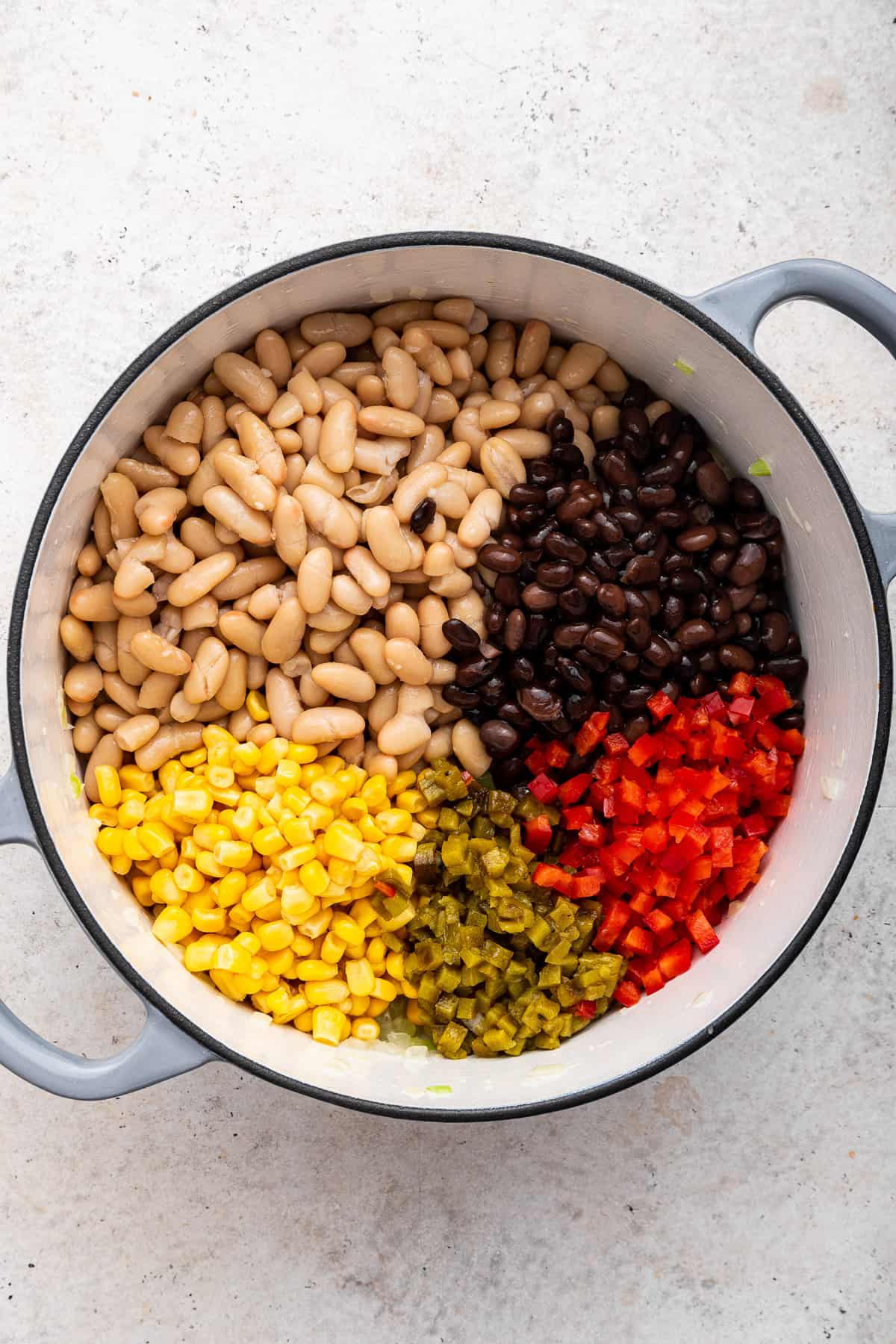 Five ingredients in the pot: black beans, corn, white beans, green chilis and red pepper dice.