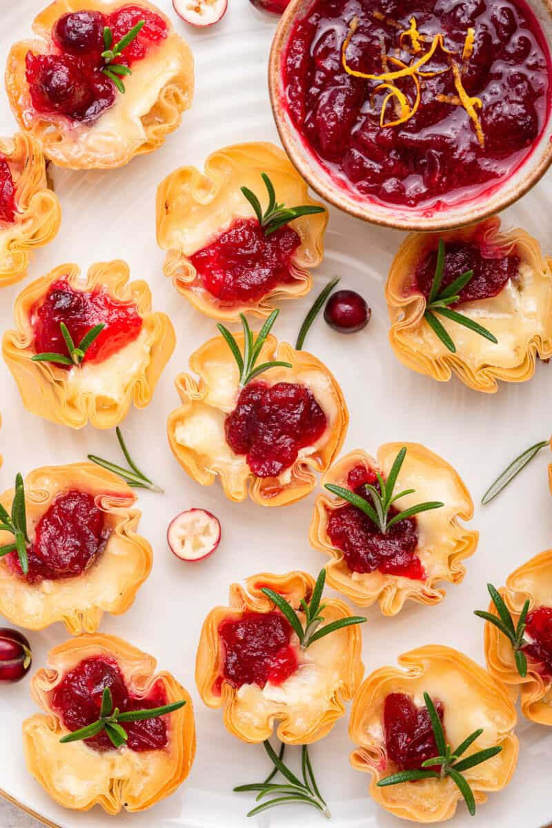 Cranberry brie bites with a bowl of cranberry sauce.