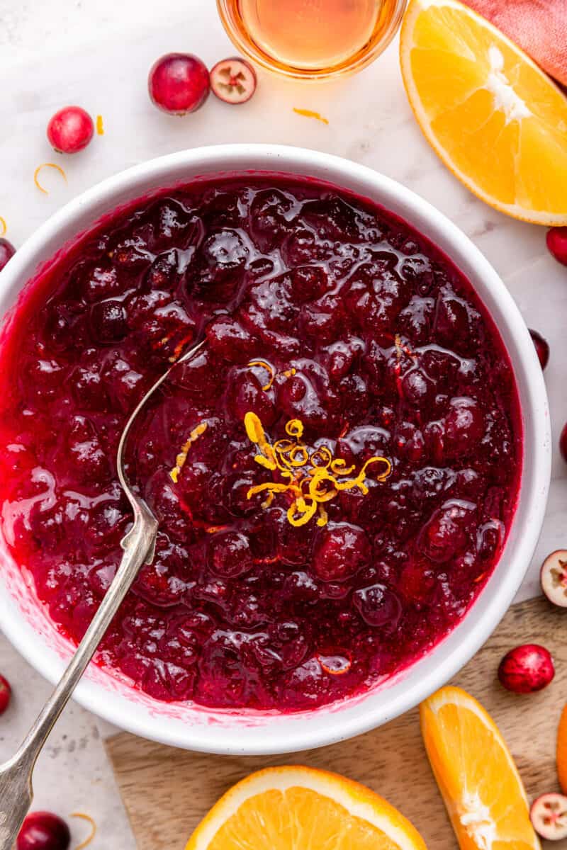 Bowl of homemade cranberry sauce with orange zest and spoon.