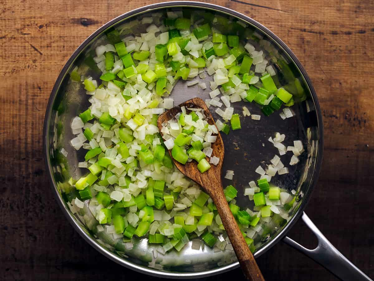 Sauteeing onion and celery in silver pan.