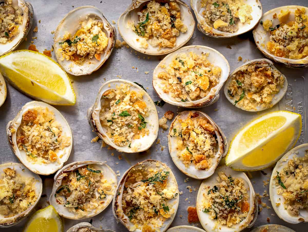 Baked clams on grey platter with lemon wedge.