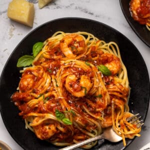 Black plate with pasta and shrimp fra diavolo.