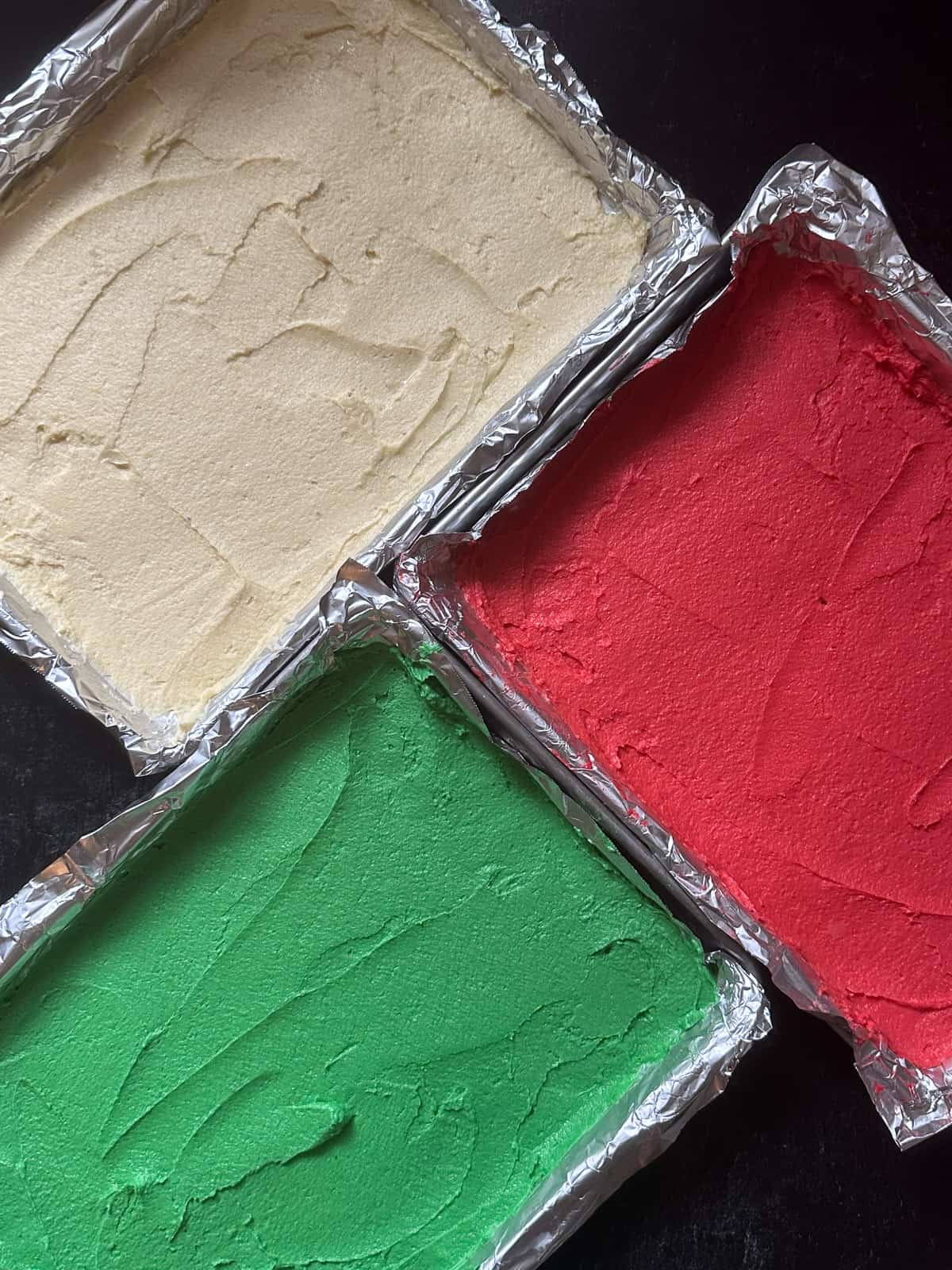 The three unbaked cake layers in red, white and green.