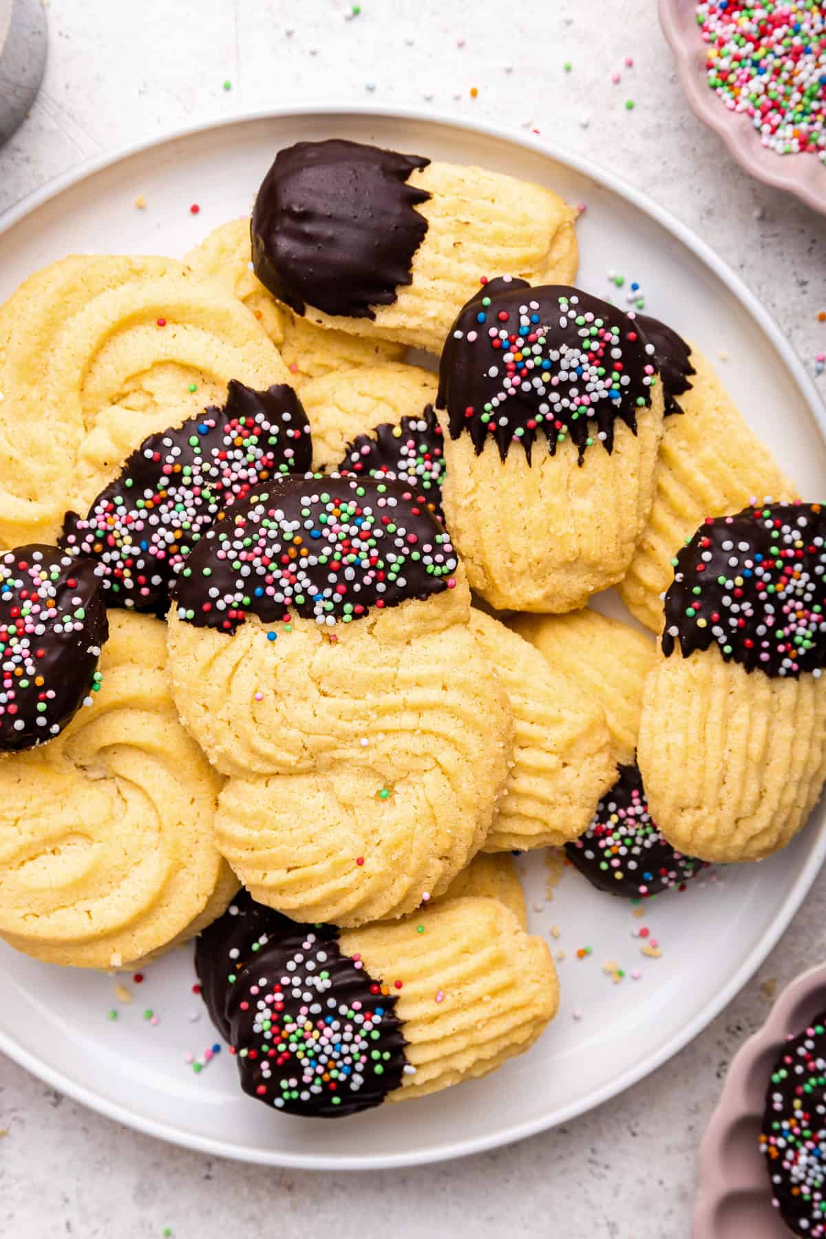 A plate of Italian butter cookies dipped in chocolate with colored nonpareils.
