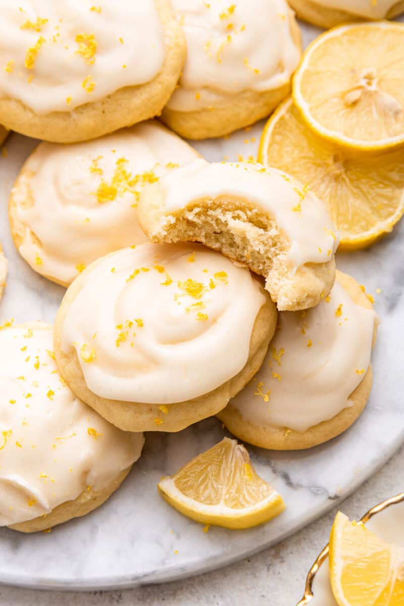Marble tray of lemon ricotta cookies with one cookie biten.