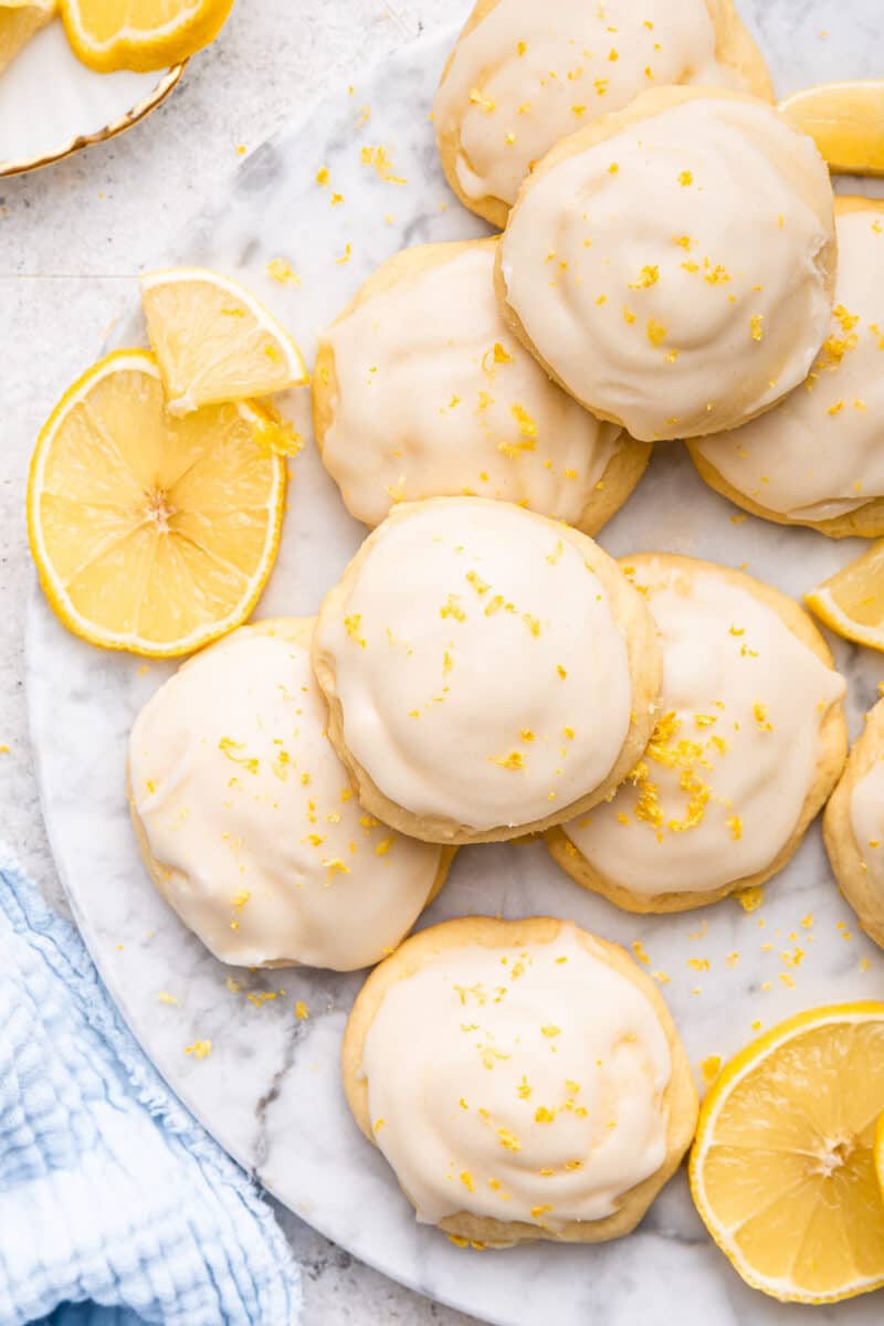 Mounds of lemon ricotta frosted cookies on marble background.