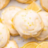Close view of lemon ricotta cookies frosted with lemon slices scattered about.