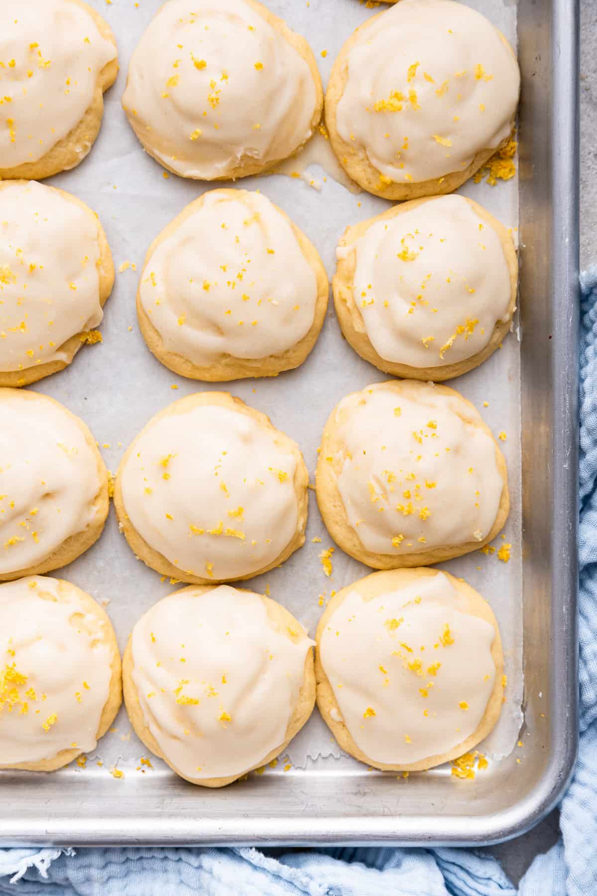 Frosted lemon ricotta cookies on parchment lined cookie sheet.