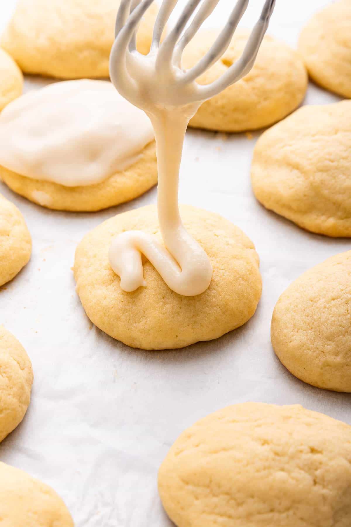 Pouring frosting over lemon ricotta cookies.