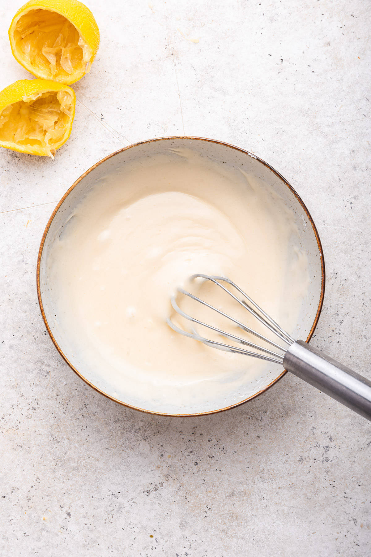 Bowl of frosting for lemon ricotta cookies with whisk.