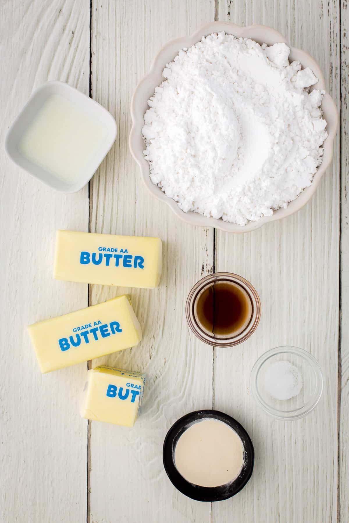 Ingredients for buttercream frosting on a white wood background.