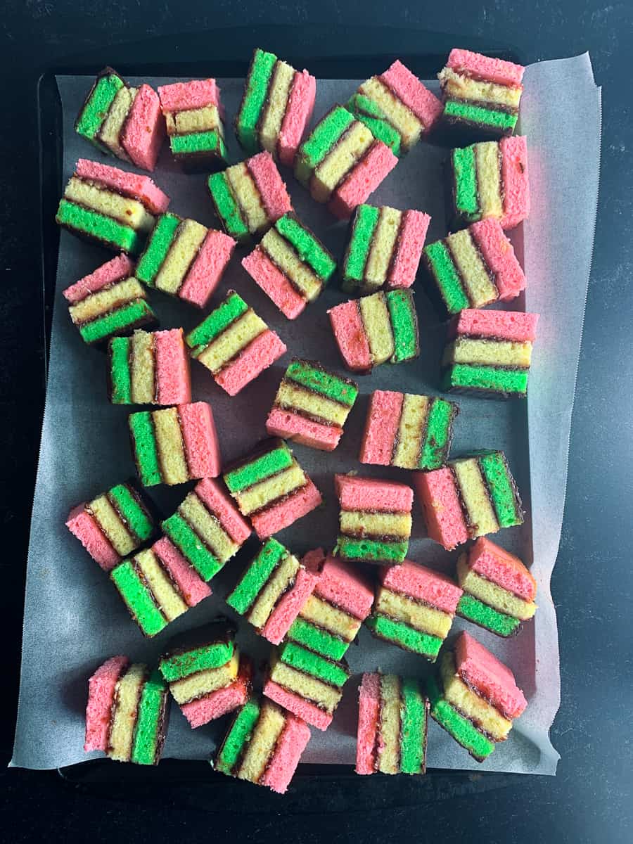 Top view of rainbow cookies on parchment lined cookie sheet.