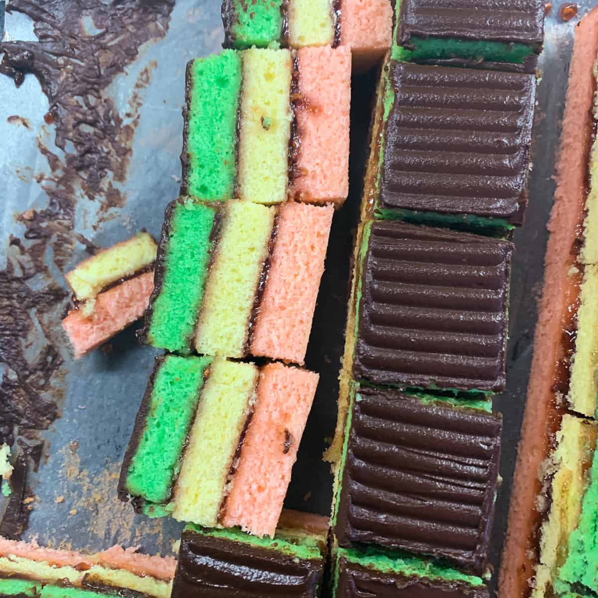 Layers of rainbow cookies are being cut.