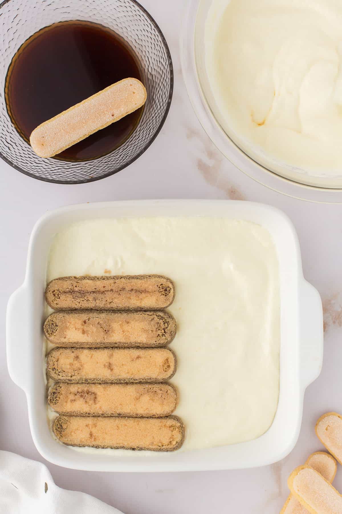 Placing second layer of ladyfingers on top of cream.