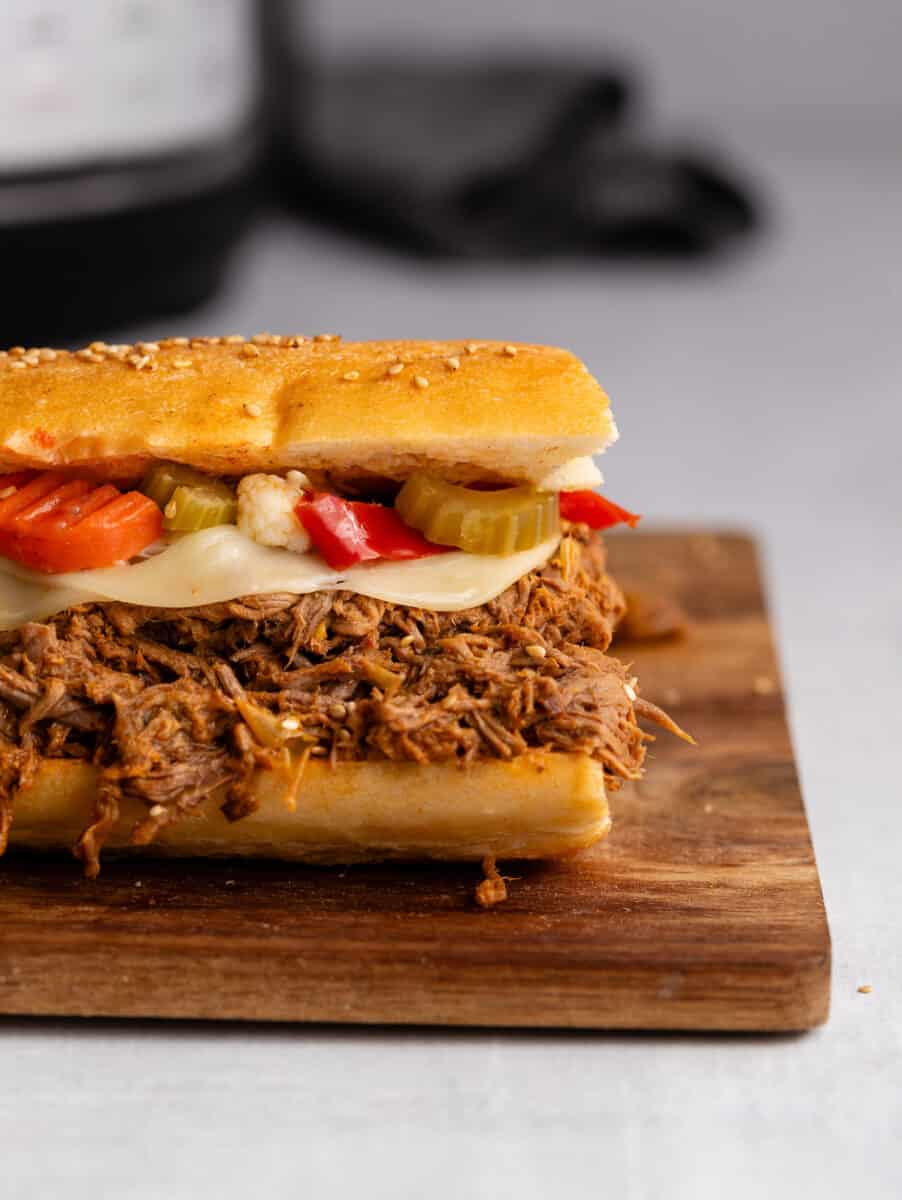 Side view of an Italian beef sandwich on a wooden board.