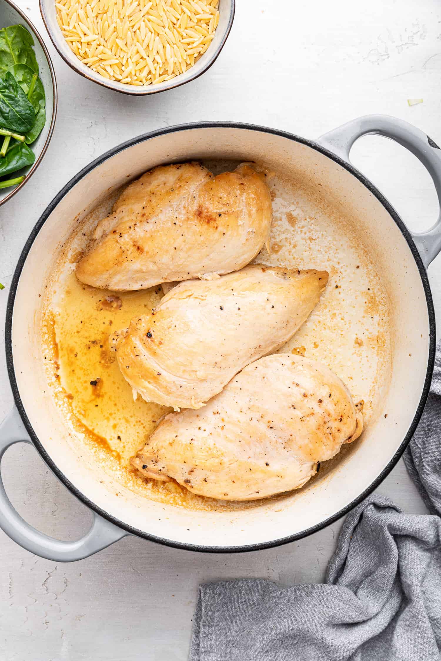 Chicken breasts cooking in pot.