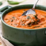 Side view of tomato florentine soup with spoon.