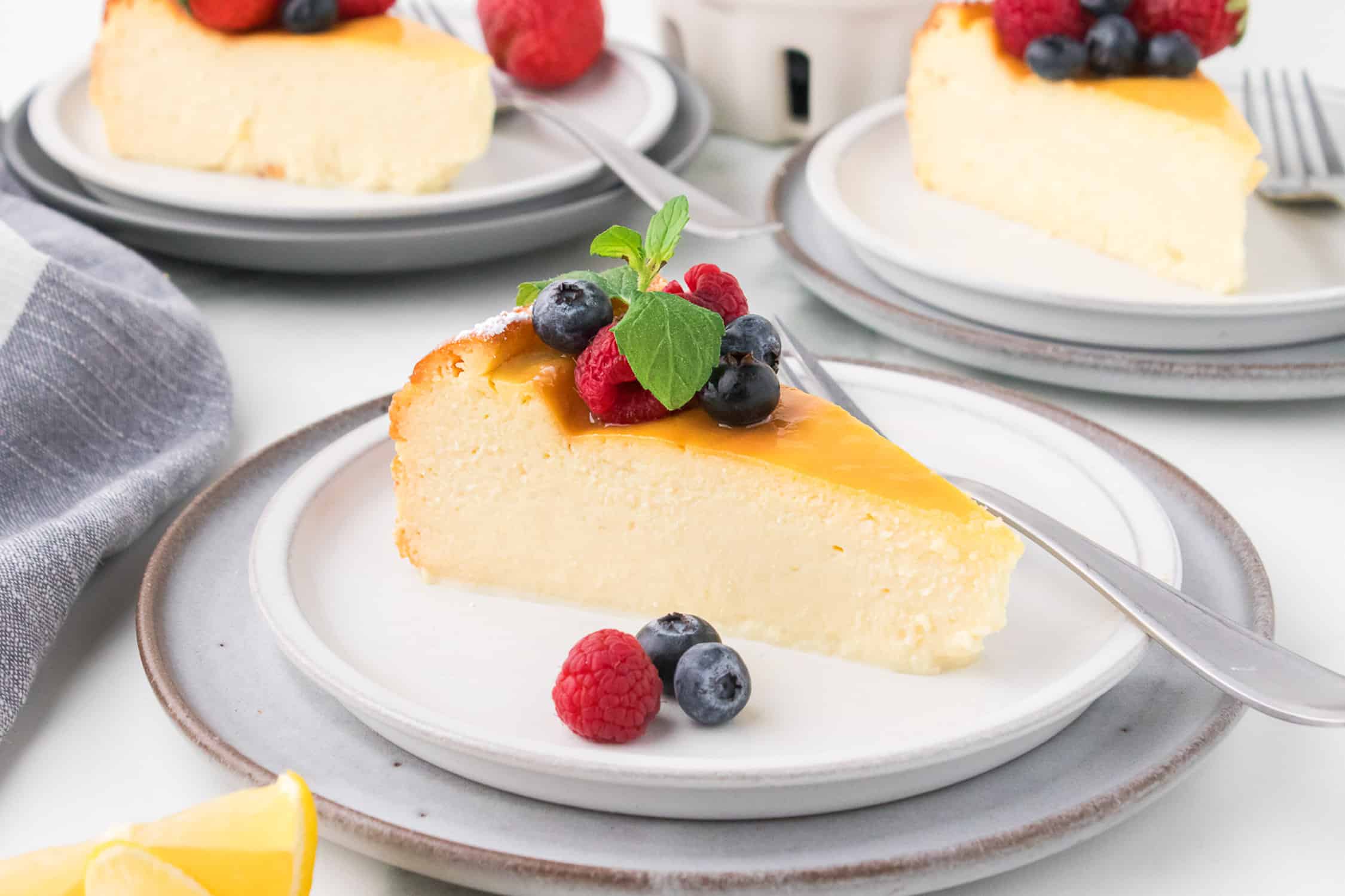 Slice of ricotta cheesecake with berries on white plate. 