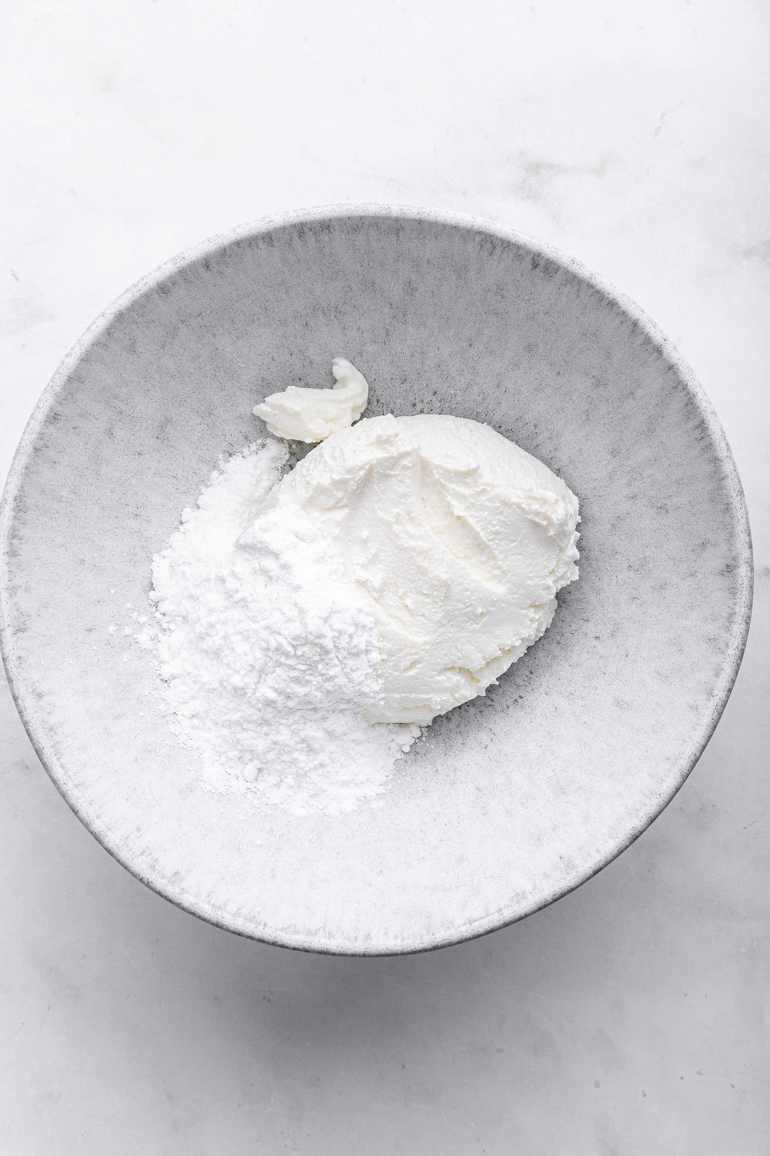 Ricotta and powdered sugar in white bowl.