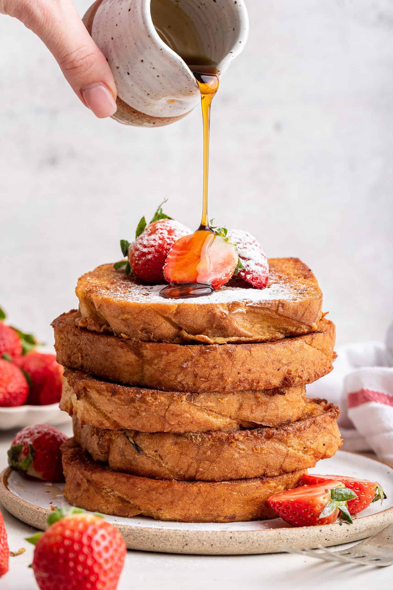 Stack of french toast with strawberries and sryup. 
