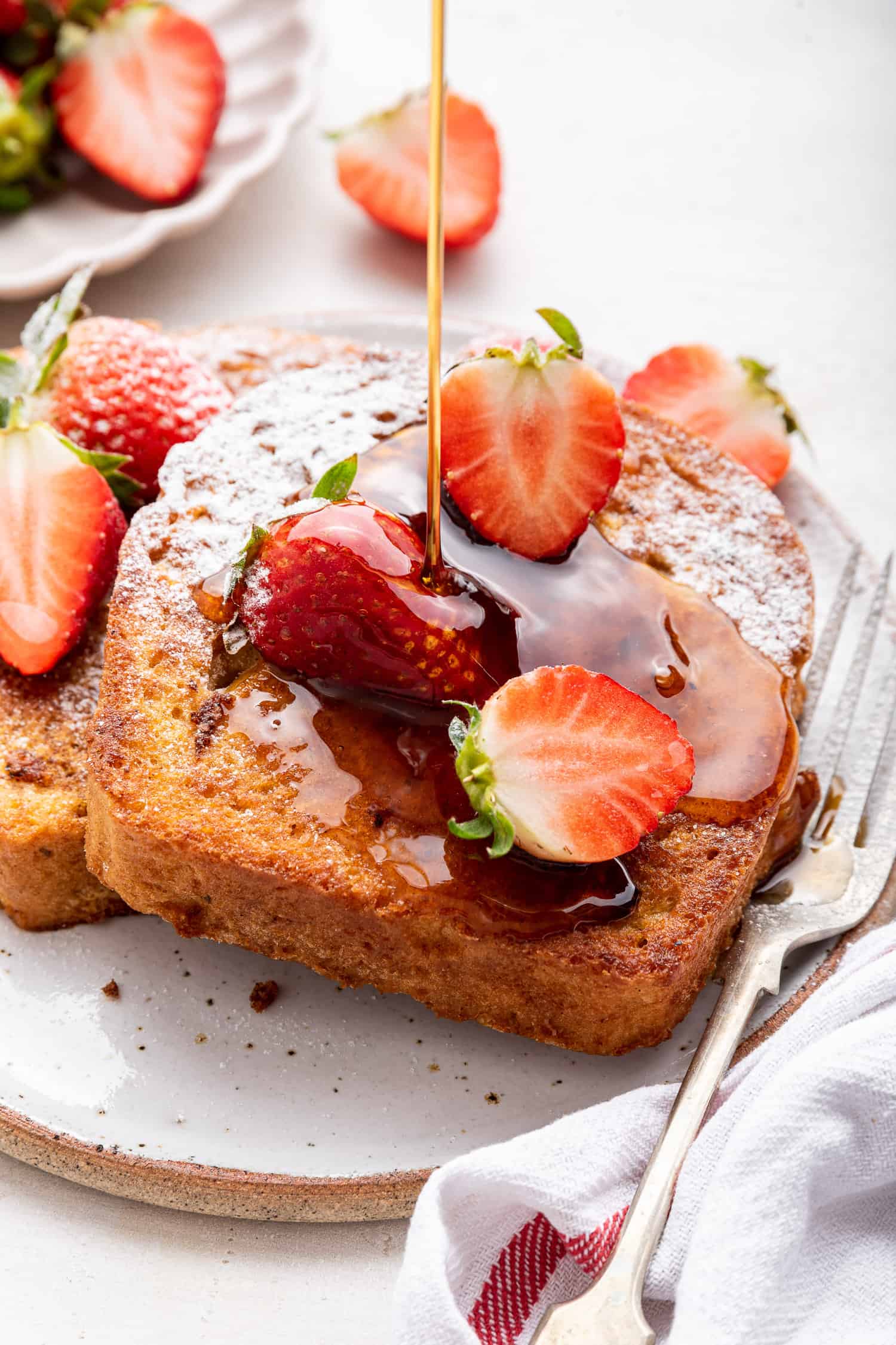 French toast with powdered sugar, strawberries, and syrup drizzle. 