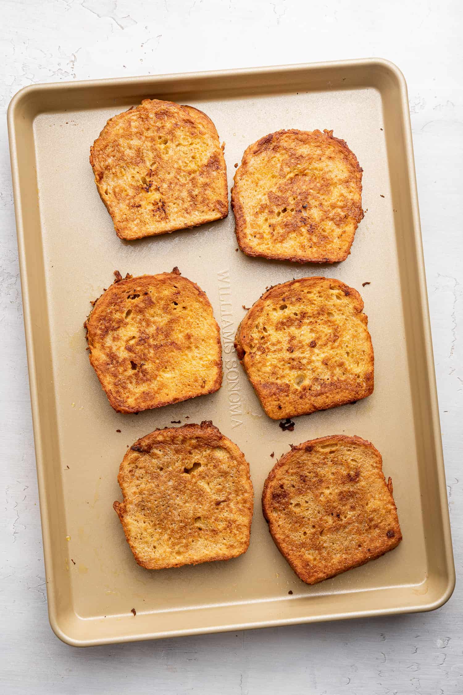 Slices of french toast on a baking sheet. 