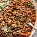 Close view of Italian lentils with serving spoon in large dish.