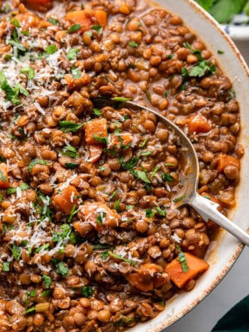 Close view of Italian lentils with serving spoon in large dish.