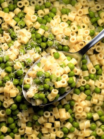 Large spoonful of pasta and peas with grated cheese.