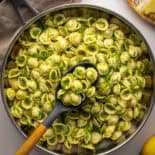 Top view of pasta with broccoli in pan with serving spoon.