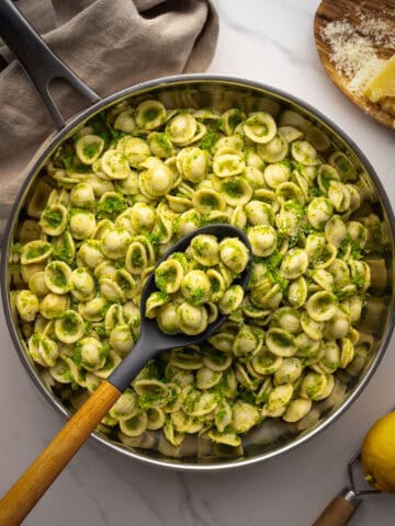 Top view of pasta with broccoli in pan with serving spoon.