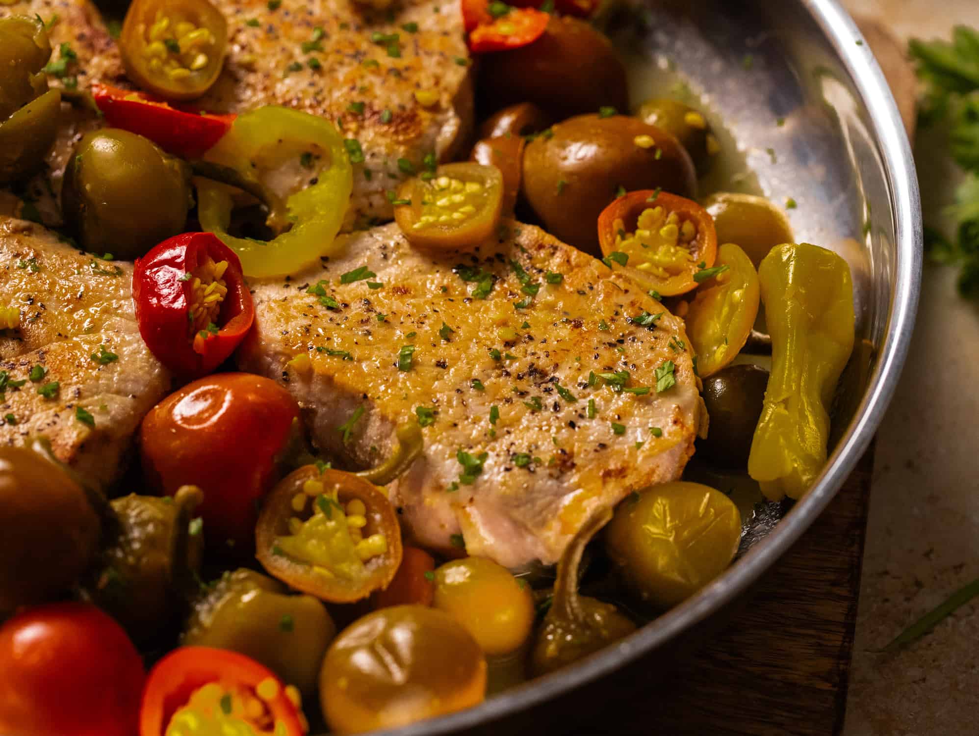 Close up of seasoned pork with peppers in pan.