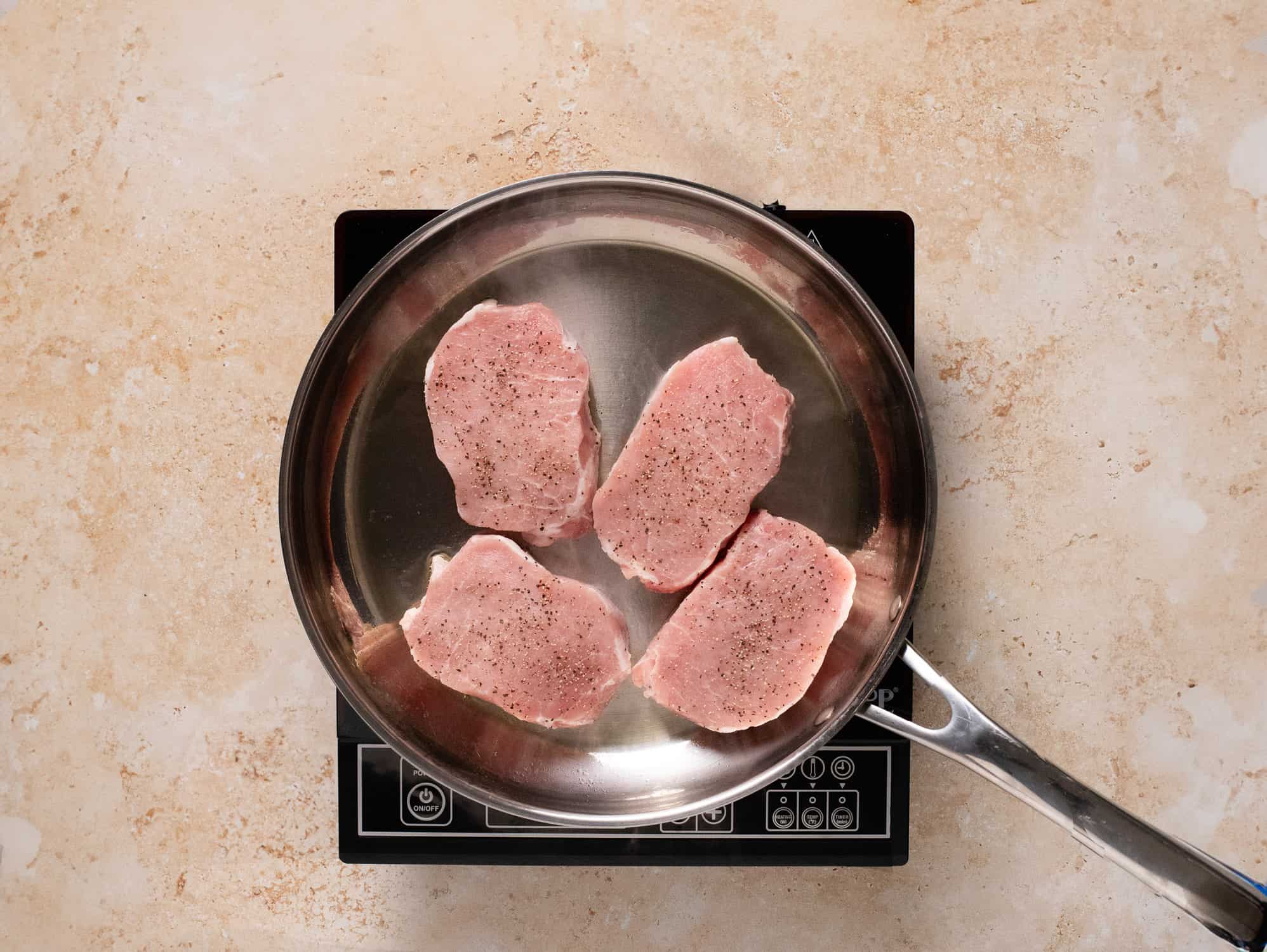 Four pork chops (boneless) into frying pan.