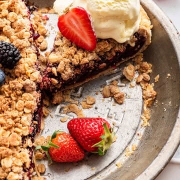 Single slice of pie cut from rest with ice cream and berries in pan.