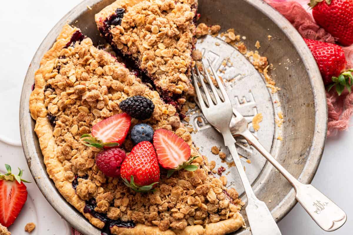 Pie topped with fresh berries in plate with forks.