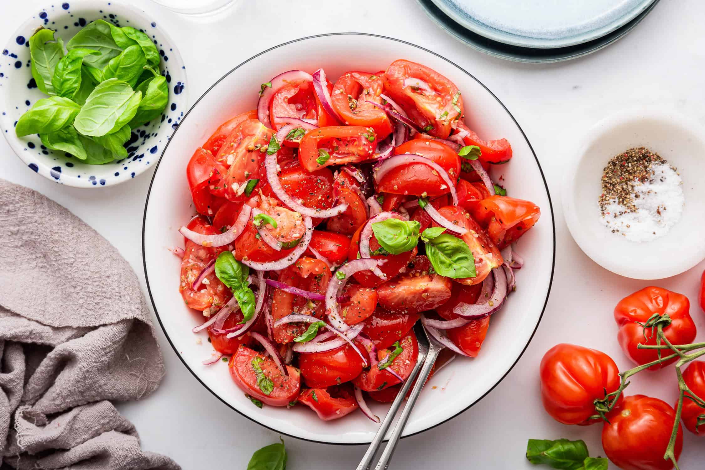 White bowl of Italian tomato salad with spoon.