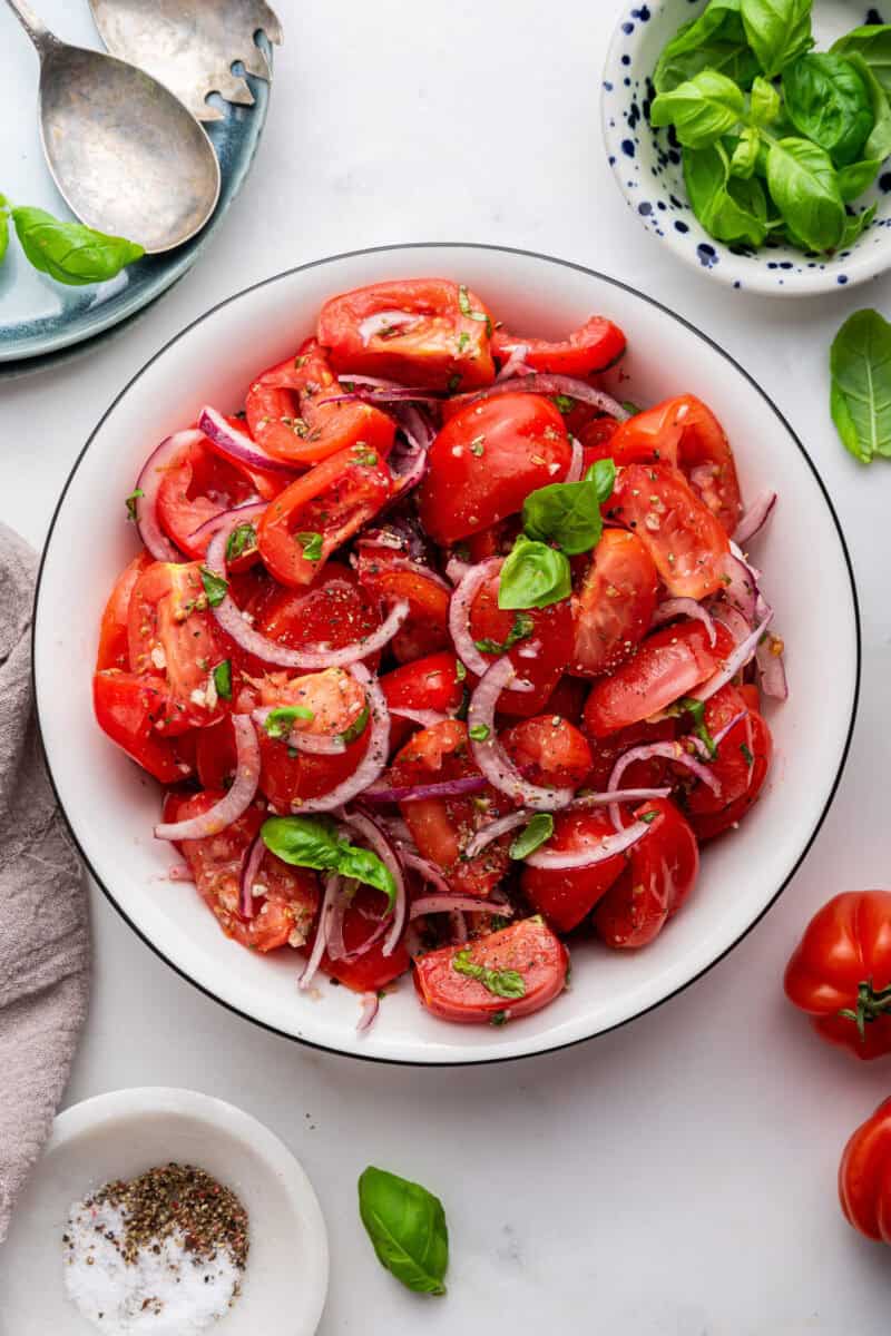 Bowl of tomato salad with basil sprinkled around.