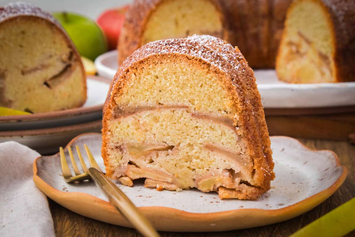 Slice of Jewish apple cake with fork on white plate.