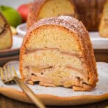 Slice of Jewish apple cake with fork on white plate.