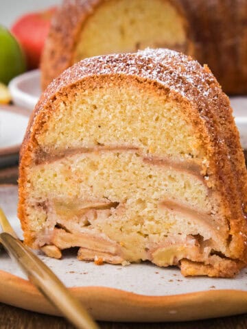 Slice of Jewish apple cake with fork on white plate.