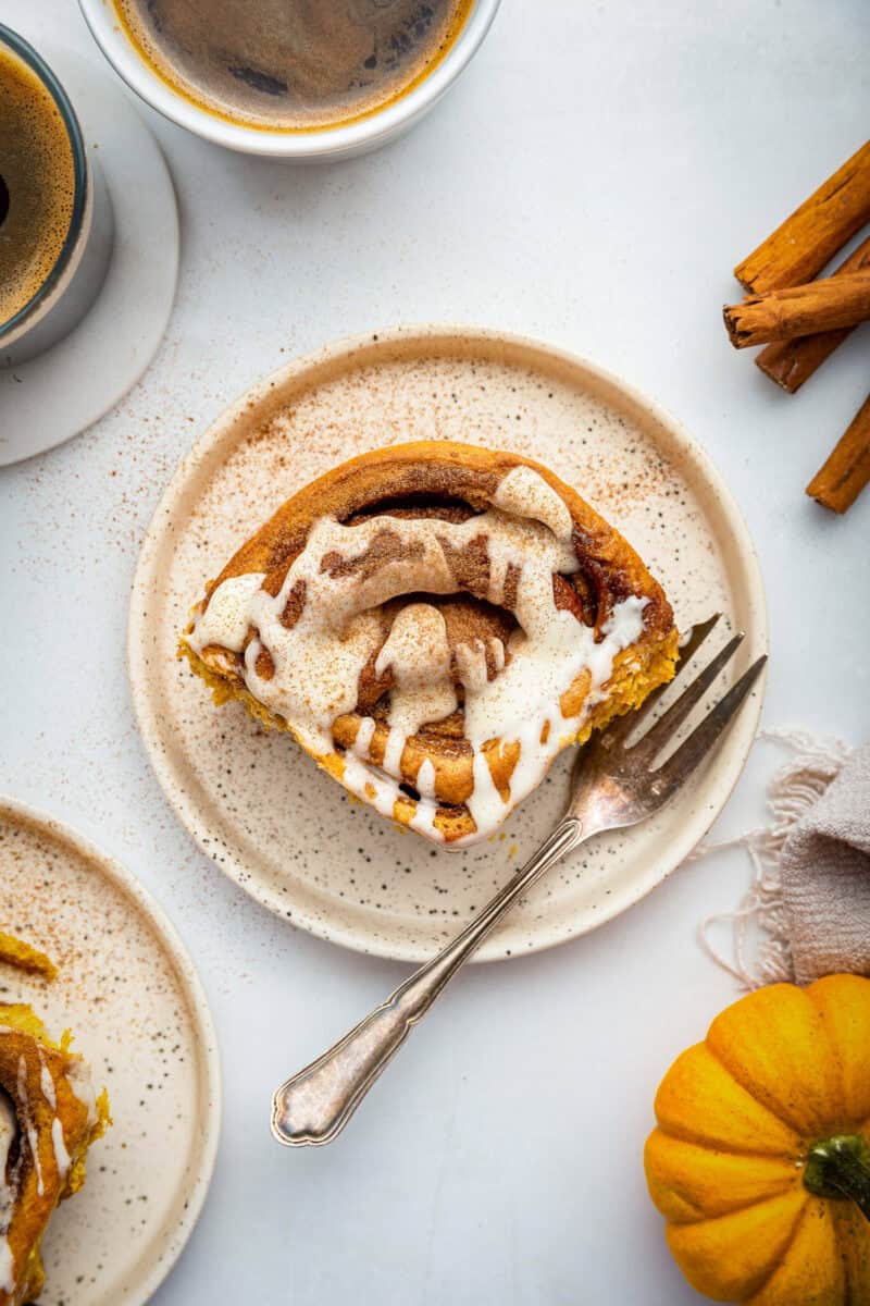 Cinnamon roll with fork on small plate.