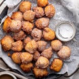 Italian sfingi on a parchment lined pan with powdered sugar.