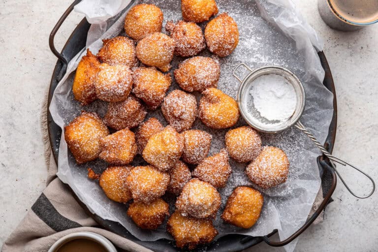 Italian sfingi on a parchment lined pan with powdered sugar.