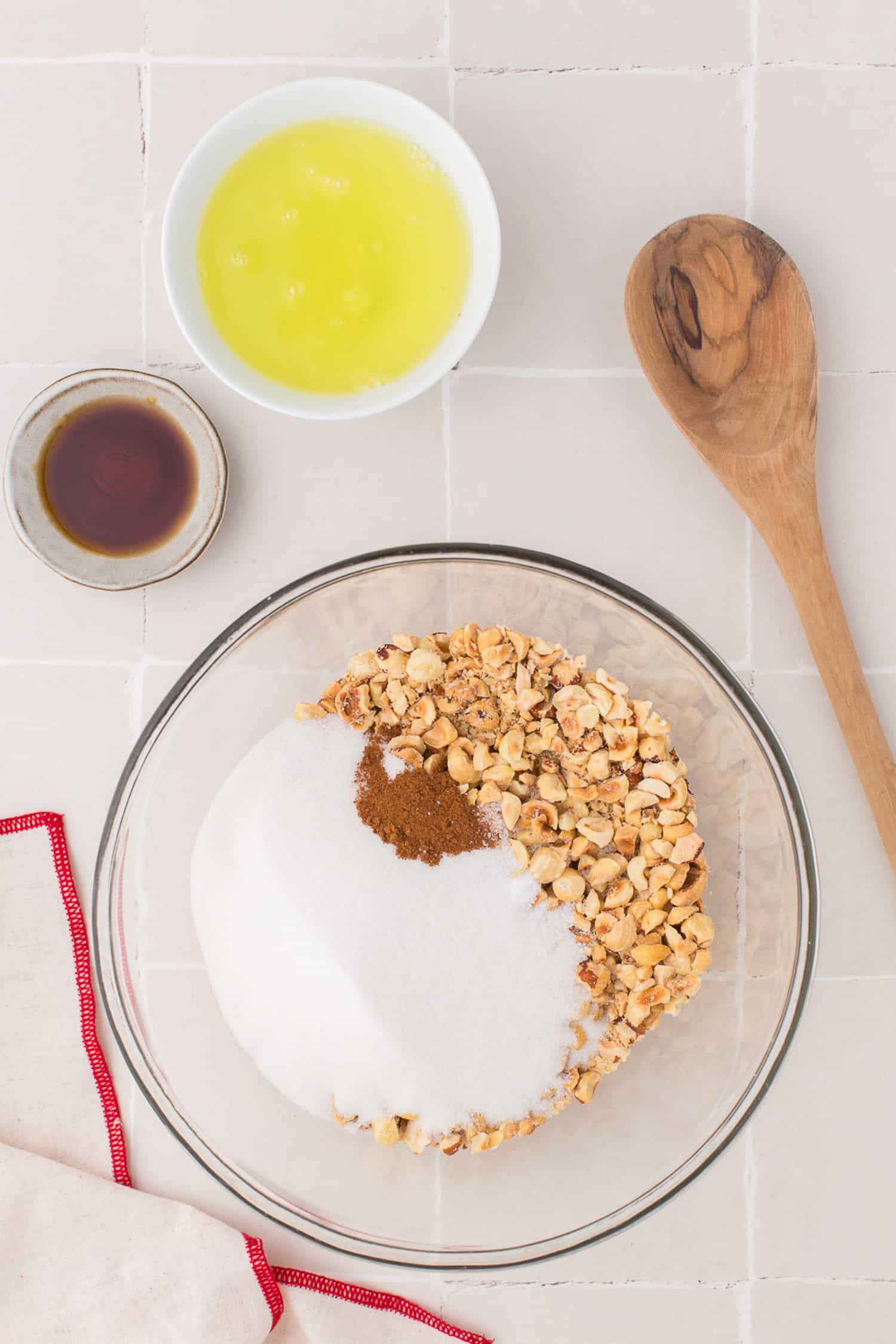 Ingredients sugar, nuts, egg white and flavoring shown with wooden spoon. 