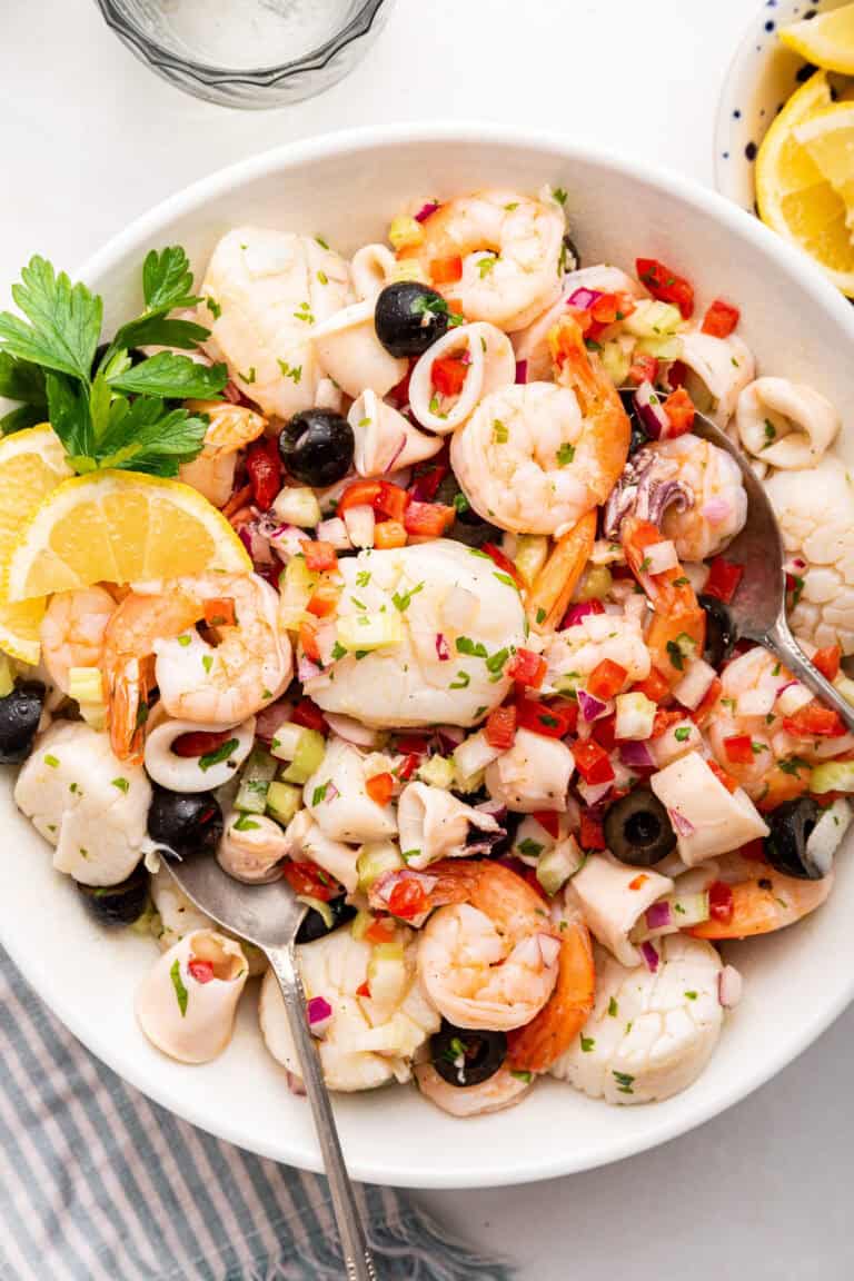 Italian seafood salad in white bowl with spoon,