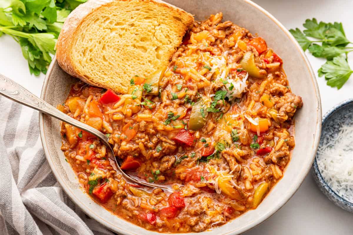 Stuffed pepper soup with bread in white bowl with spoon.